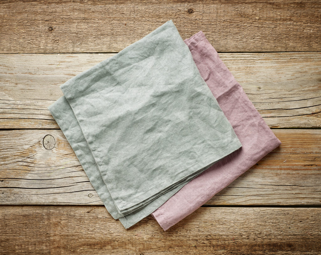folded linen napkins on old wooden table, top view